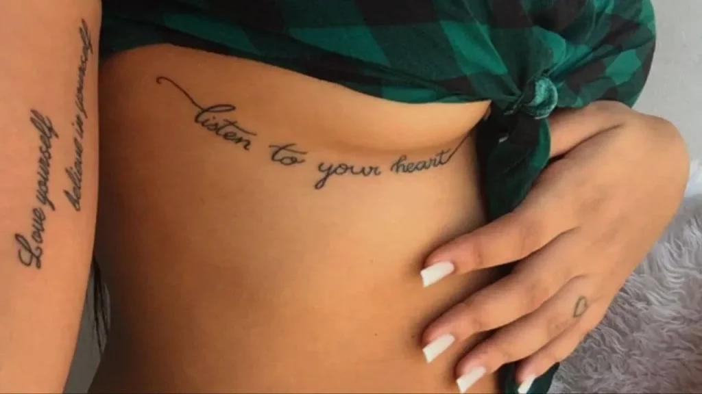 A woman showcasing a fine-line script design on her ribcage, a protected placement for Memorial Handwriting Tattoos.