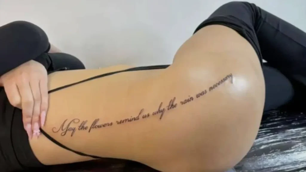 A woman showcasing a long, fine-line script design on her hip and lower back, a graceful placement for Memorial Handwriting Tattoos.