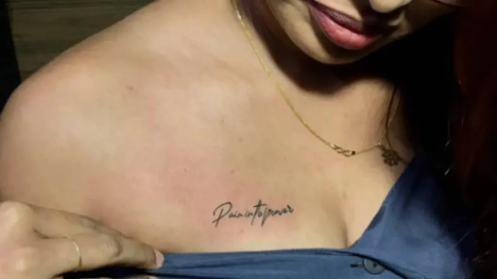 A woman showcasing a fine-line script design on her upper chest, an ideal placement for meaningful Memorial Handwriting Tattoos.