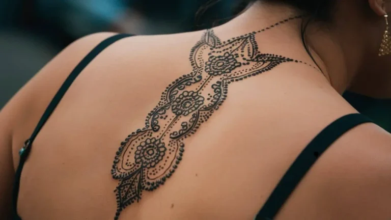 A wide and detailed Spine Chakra Sacred Geometry Tattoo featuring intricate dotwork and mandala patterns on a woman's upper back.