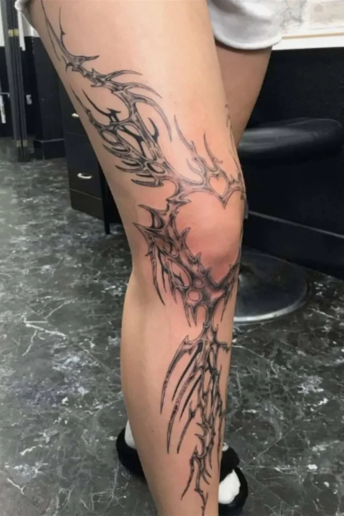 A bold cybersigilism leg tattoo featuring sharp, organic black-ink lines and a heart motif, perfect for a cohesive Y2K sticker sleeve tattoo aesthetic.
