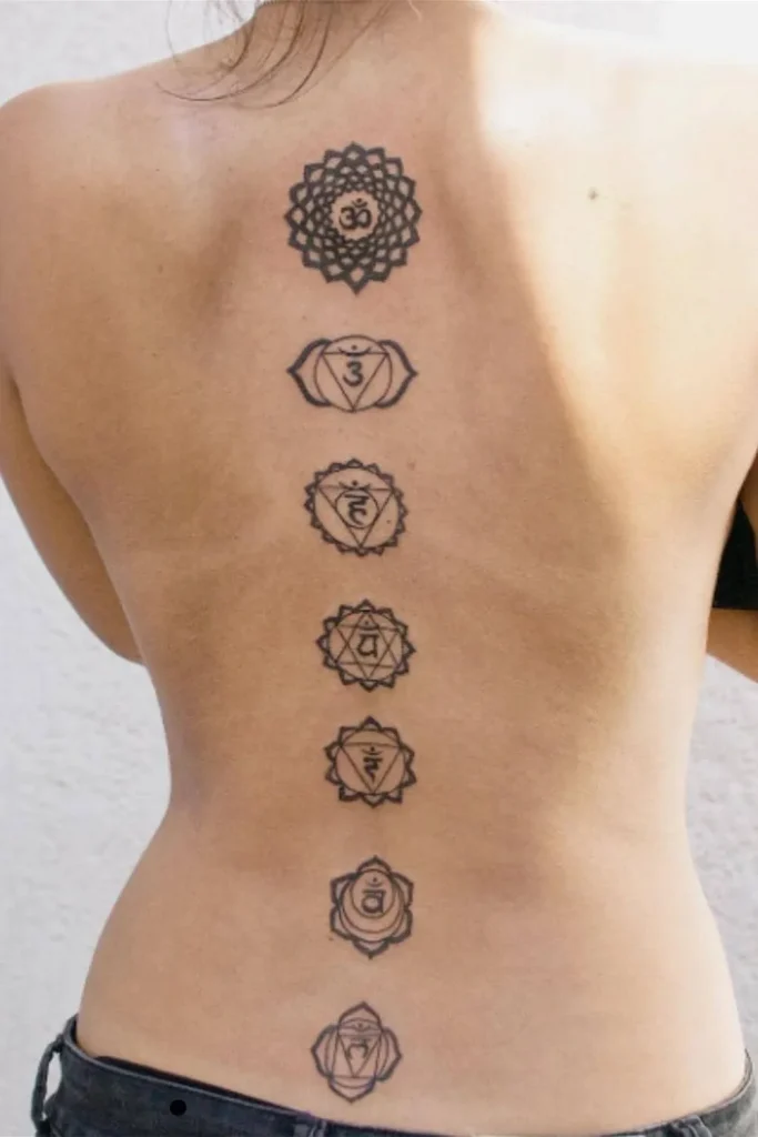 A vertical Spine Chakra Sacred Geometry Tattoo featuring seven detailed black-ink symbols from the upper neck down to the mid-back on a woman's spine.