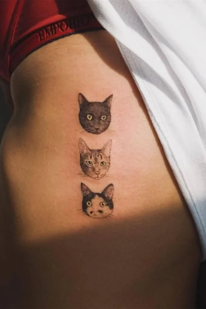 A vertical row of three hyper-realistic Micro Realism Pet Memorial Tattoos on a person's side, featuring three different cat portraits with detailed fur textures and bright eyes.