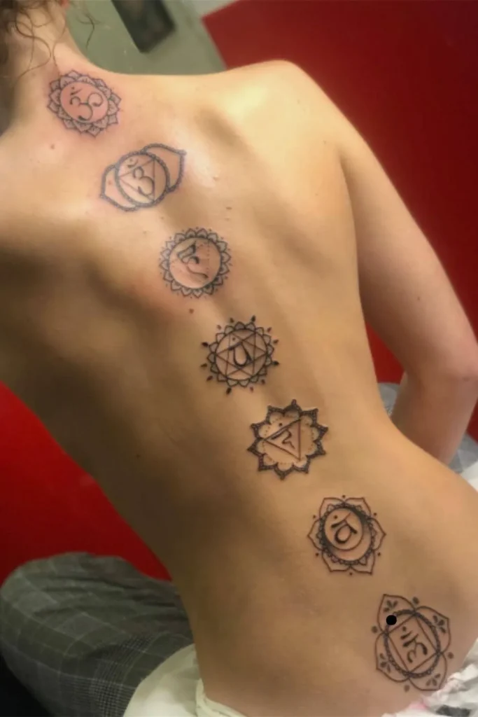 A vertical Spine Chakra Sacred Geometry Tattoo featuring seven intricate mandala-style symbols aligned down a woman's back.