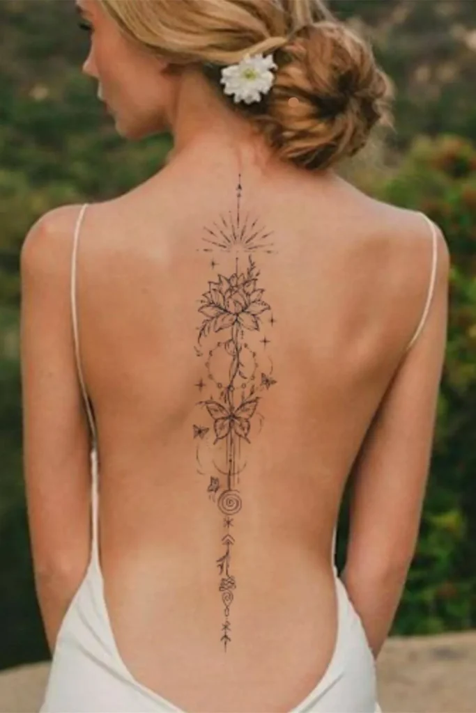 A delicate fine-line Spine Chakra Sacred Geometry Tattoo featuring a lotus, butterfly, and geometric symbols vertically aligned on a woman's back.