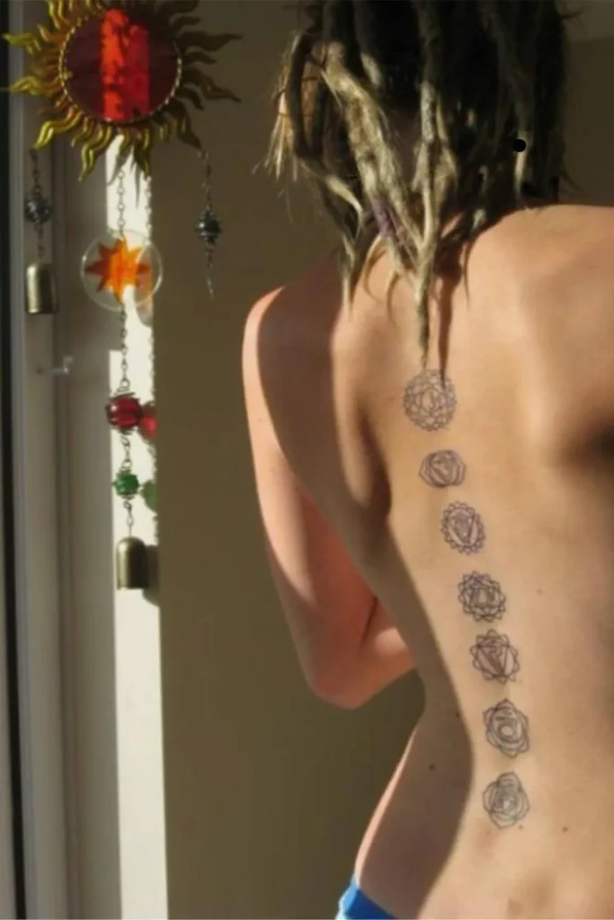 A vertical, fine-line Spine Chakra Sacred Geometry Tattoo featuring seven circular symbols following the curve of a woman's back.