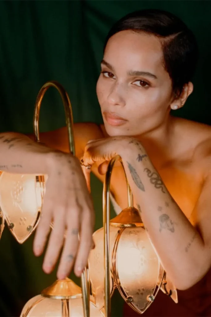 Zoe Kravitz showcases a cohesive Y2K sticker sleeve tattoo aesthetic with fine-line patchwork designs on her forearms.