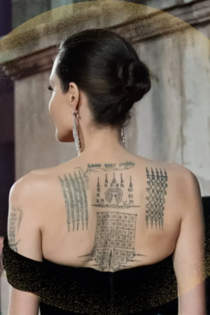 A close-up view of the tattoos on Angelina Jolie's back, featuring sacred Thai symbols and gothic script, highlighting the Angelina Jolie Stay Gold Tattoo Meaning.
