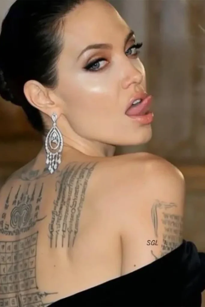 A close-up portrait of Angelina Jolie displaying her sacred back and arm tattoos, providing a historical context for the Angelina Jolie Stay Gold Tattoo Meaning.