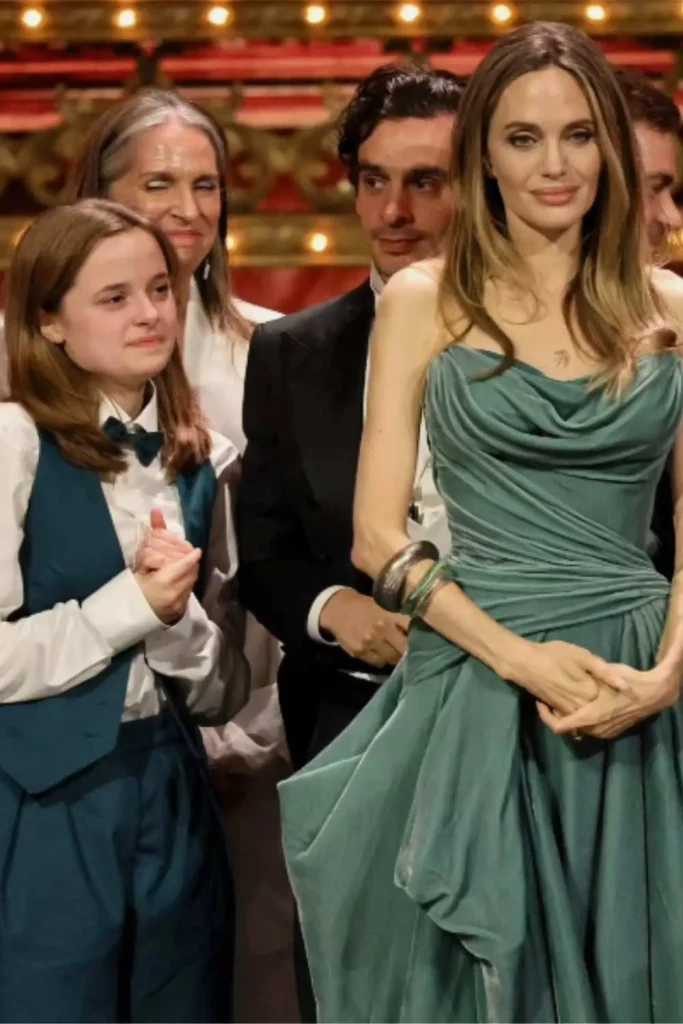 Angelina Jolie in a green gown standing with her daughter Vivienne, representing the family bond behind the Angelina Jolie Stay Gold Tattoo Meaning.